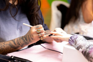 Close up shot of a nail artist using a brush to create a design on a finger nail of a client.