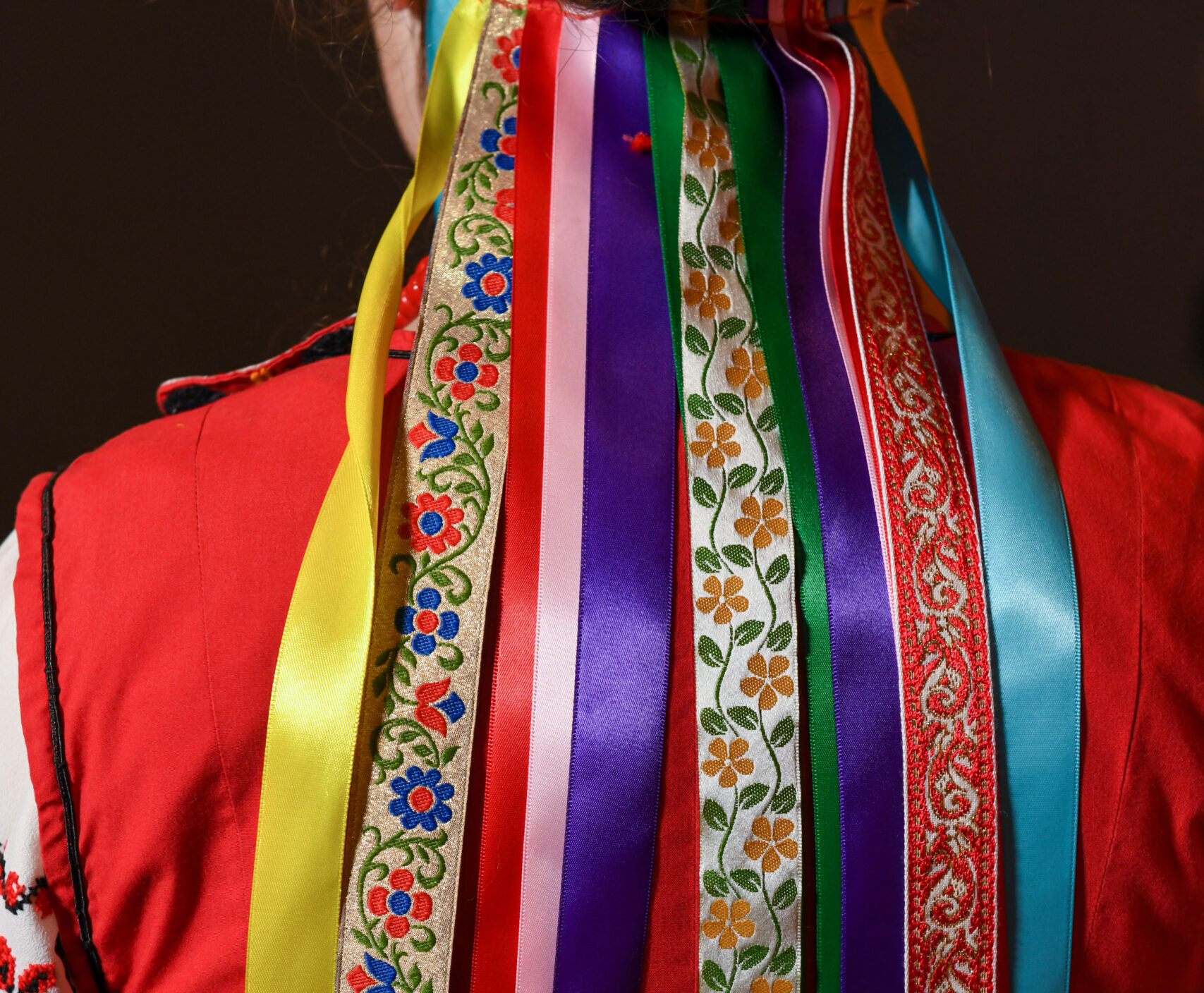colorful ribbons hang from the bottom of a headpiece and fall from the dancer's neck down her back.