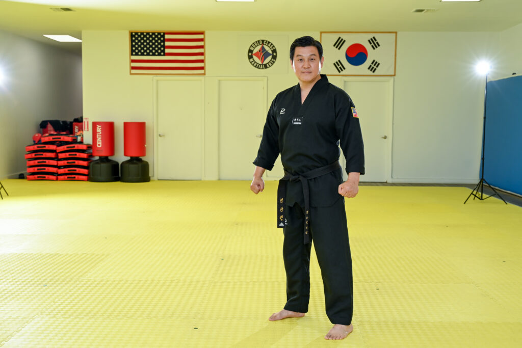 Sangwon Jeong stands in his Taekwondo uniform with his arms in fists at his side.