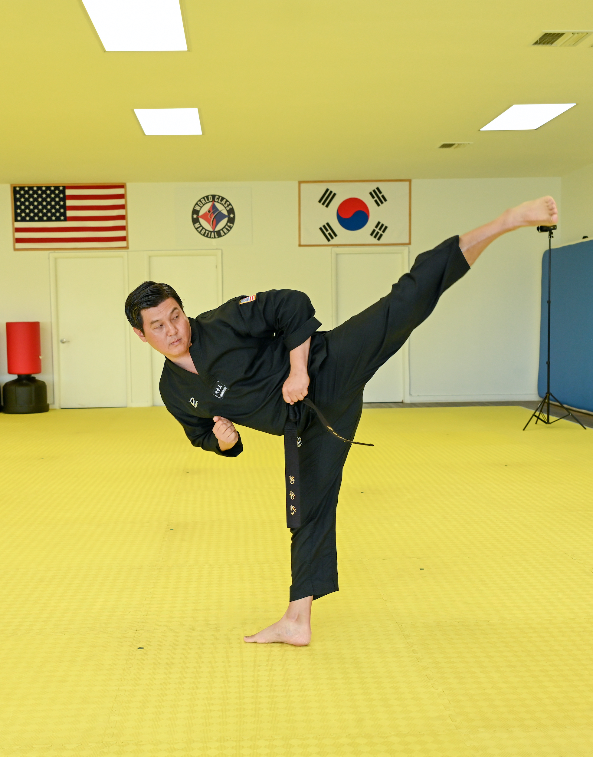 Master Jeong kicks with one leg high in the air.