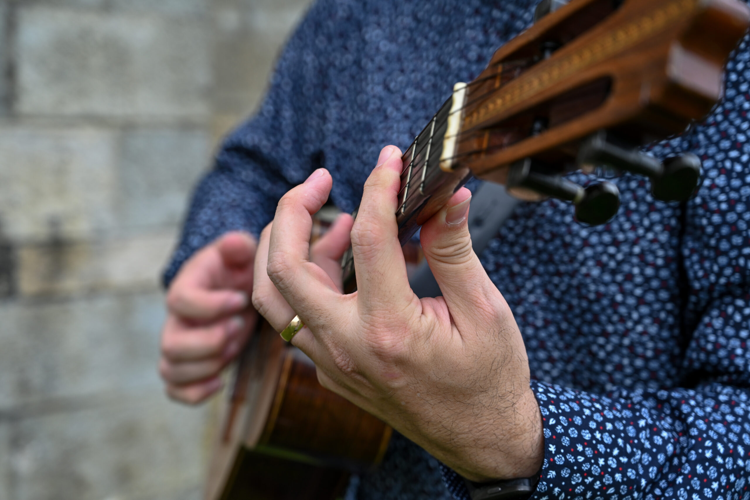 A close up of Henry's fingers on the neck of the cuatro guitar as he strums.