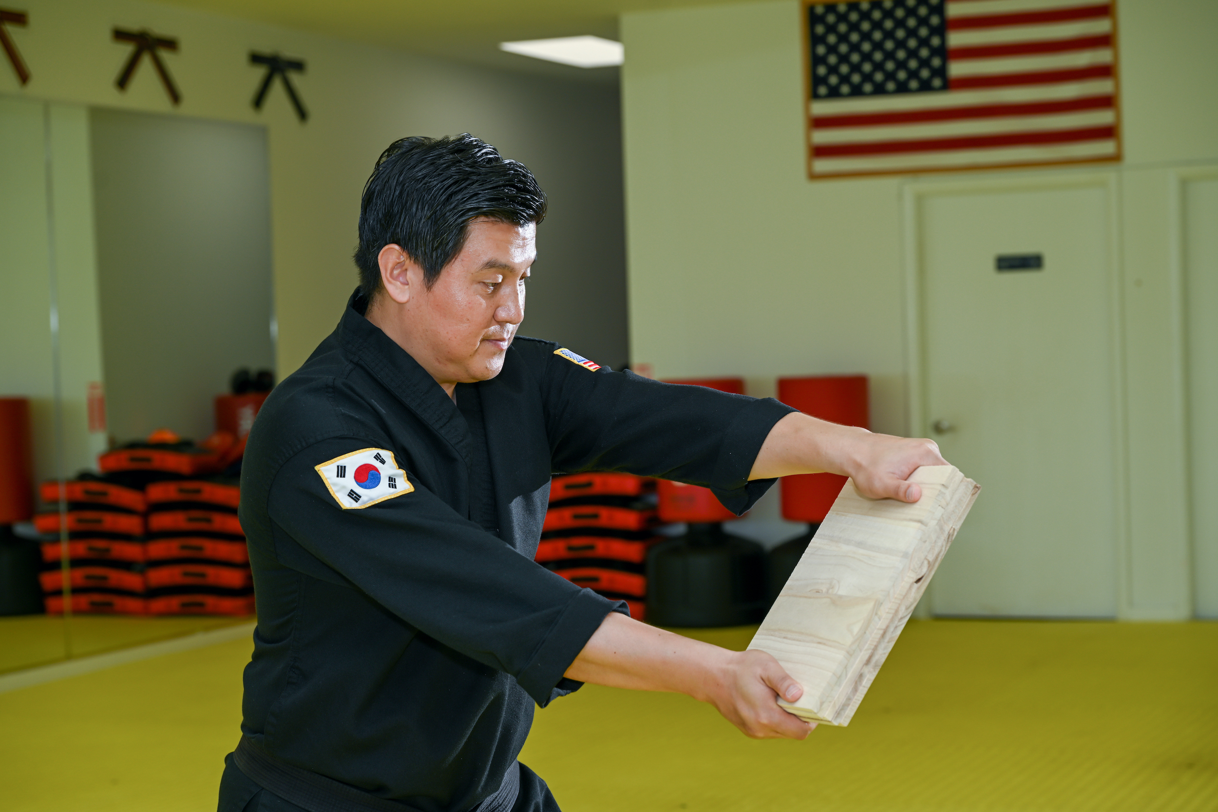 Master Jeong holds up a wood board between his hands.