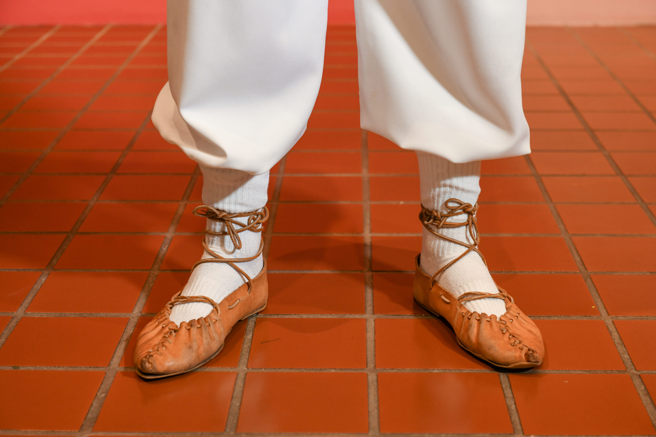 A close up of the men's traditional dancing slippers made of leather with straps that tie around the ankle.