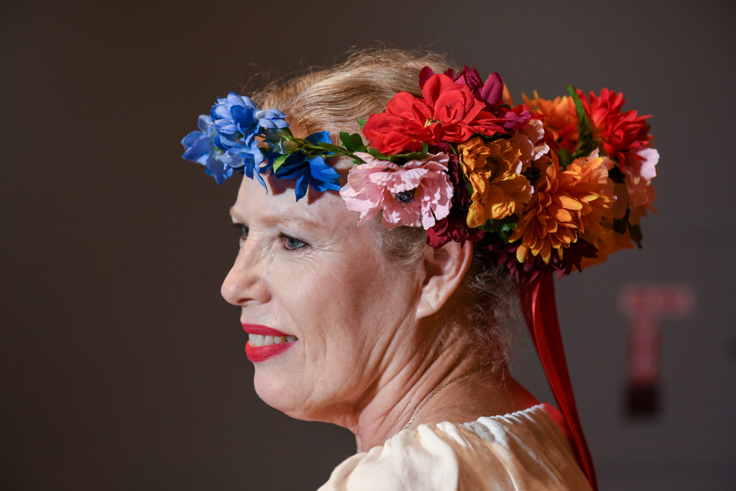 Donna wears a colorful flower headband and looks over her shoulder.