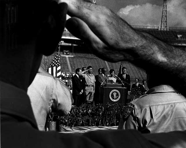 Veterans salute President Kennedy in the Orange Bowl Stadium. At the podium with President and Mrs. Kennedy are from left: Miami Mayor Robert King High, Manuel Franciso Artime Buesa, M. D. (political leader of Brigade 2506) and Jose Miro Cardona (head of the exile group, Cuban Revolutionary Council). December 29, 1962. Charles Trainor, photographer. Miami News Collection, HistoryMiami. 1989-011-21744.