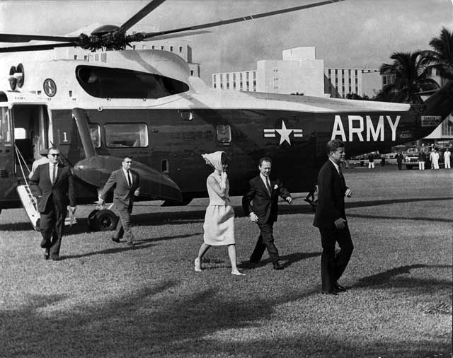 President and Mrs. Kennedy, accompanied by Miami Mayor Robert King High, walk towards the ceremony honoring the returning Bay of Pigs veterans in the Orange Bowl Stadium. At right in the background is Pierre Salinger, White House Press Secretary. December 29, 1962. Toby Massey photographer. Miami News Collection, HistoryMiami. 1989-011-4469.