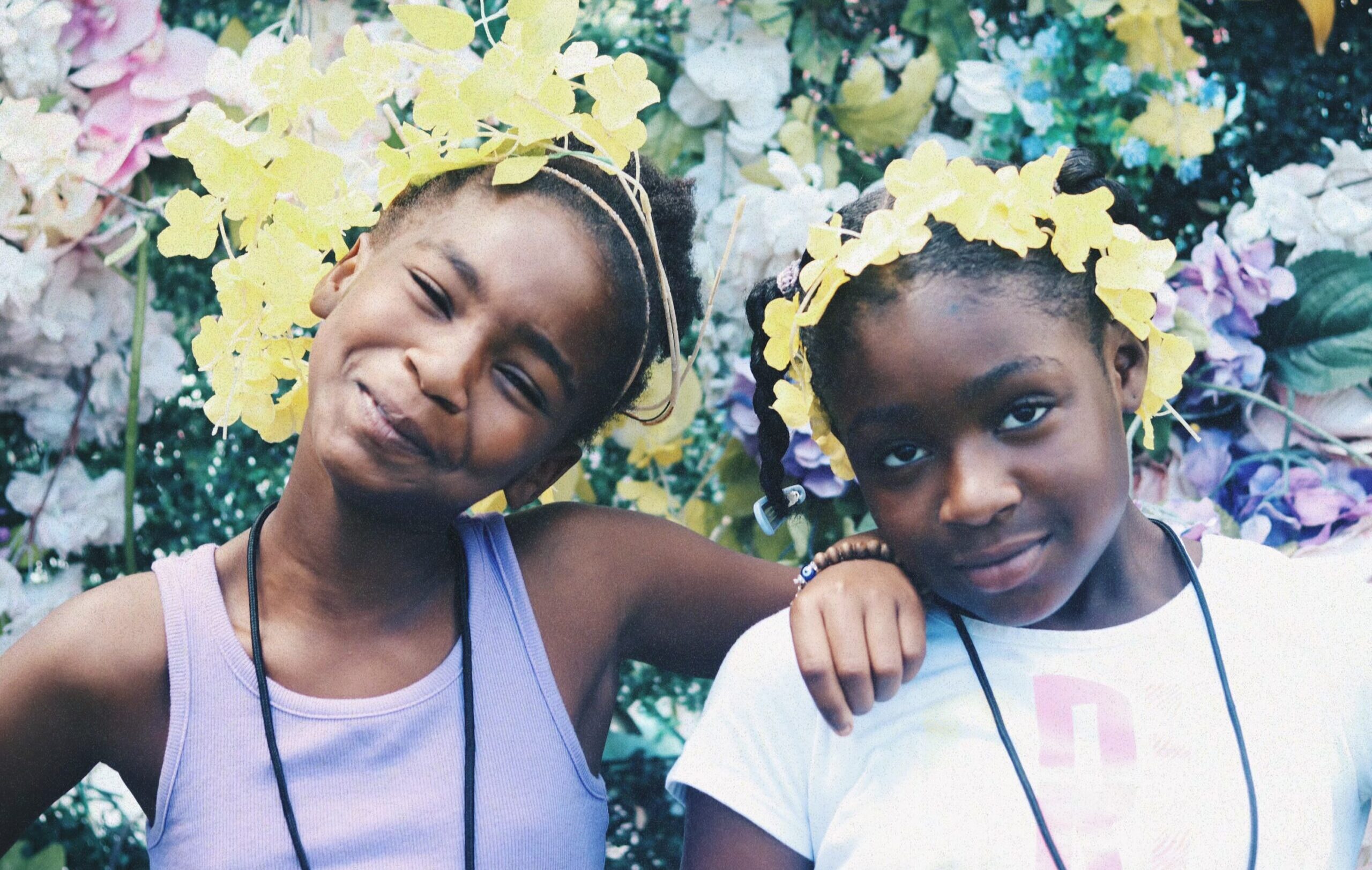 Two young girls smiling with flowers in their hair.