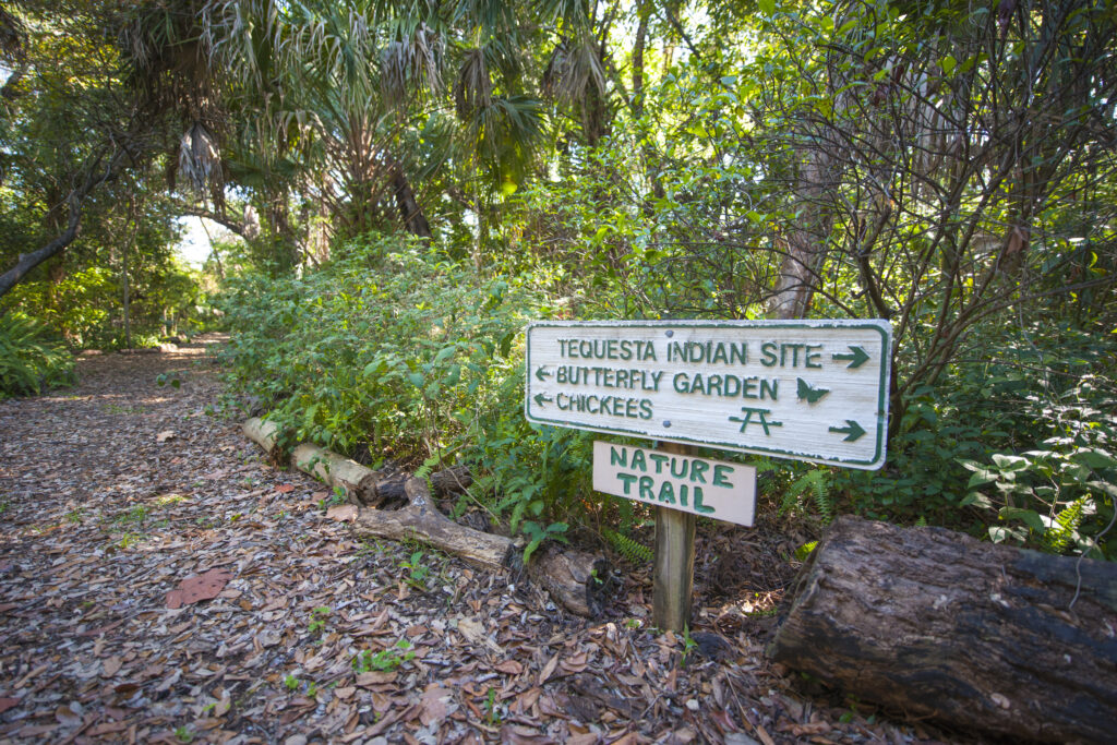 A directional signpost stands in front of a lush green forest. The sign reads "Nature Trail." Courtesy of GMCVB/miamiandbeaches.com