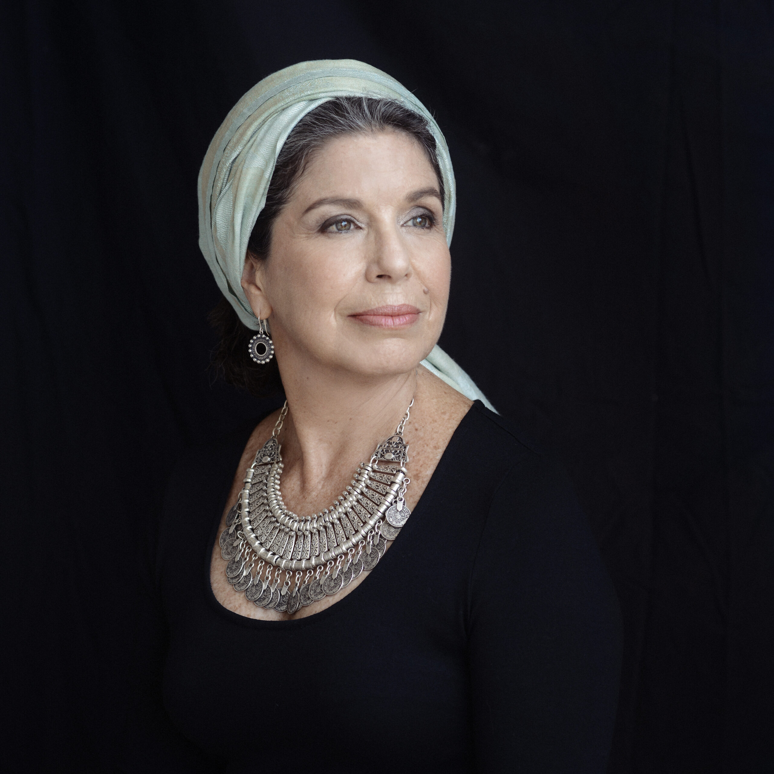 A headshot of Susana Behar Levy wearing a white turban and a black top with silver necklace.