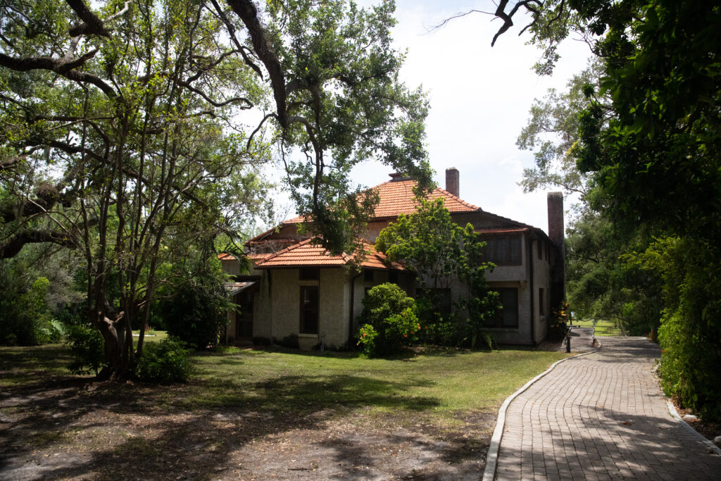 A two-story house sits on a grassy lawn surrounded by trees. Photo courtesy of the GMCVB – http://MiamiandMiamiBeach.com