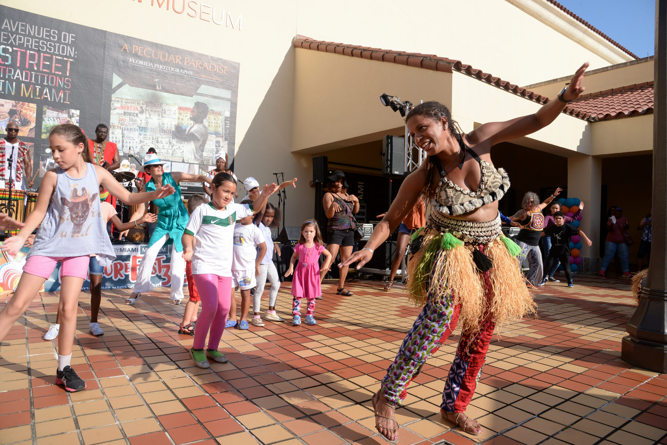 A dancer from the Delou Africa ensemble leads a workshop with a group of children who are dancing along