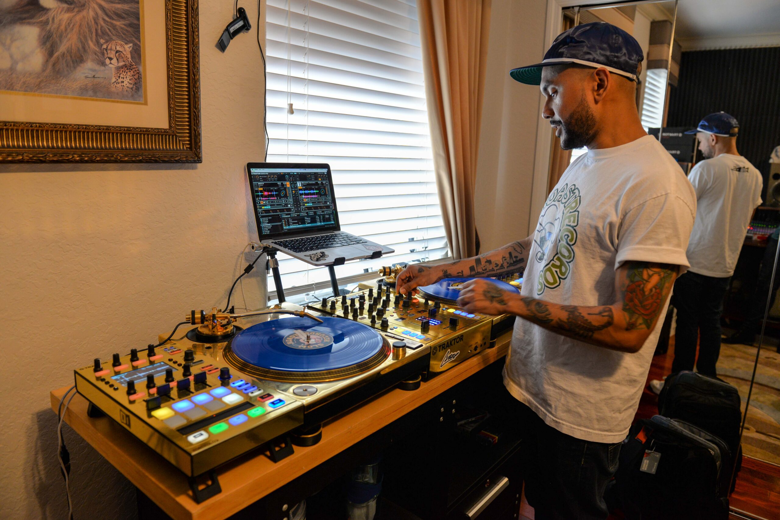 DJ Craze stands in front of his turntables with his hands on the switches in the middle.