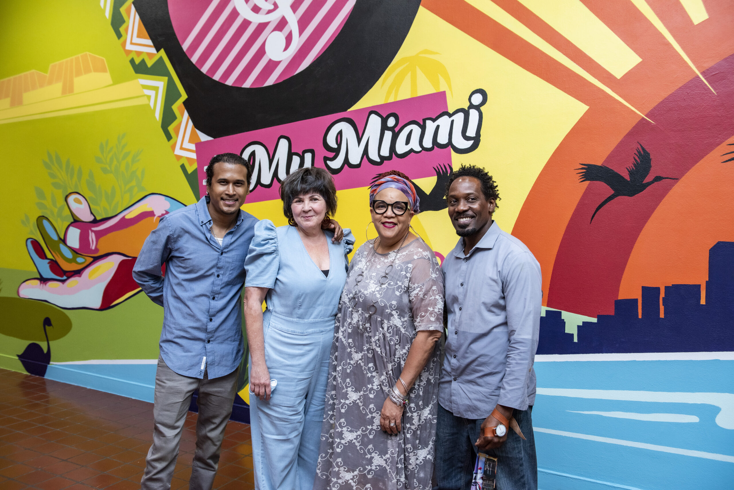 four people in front of a mural