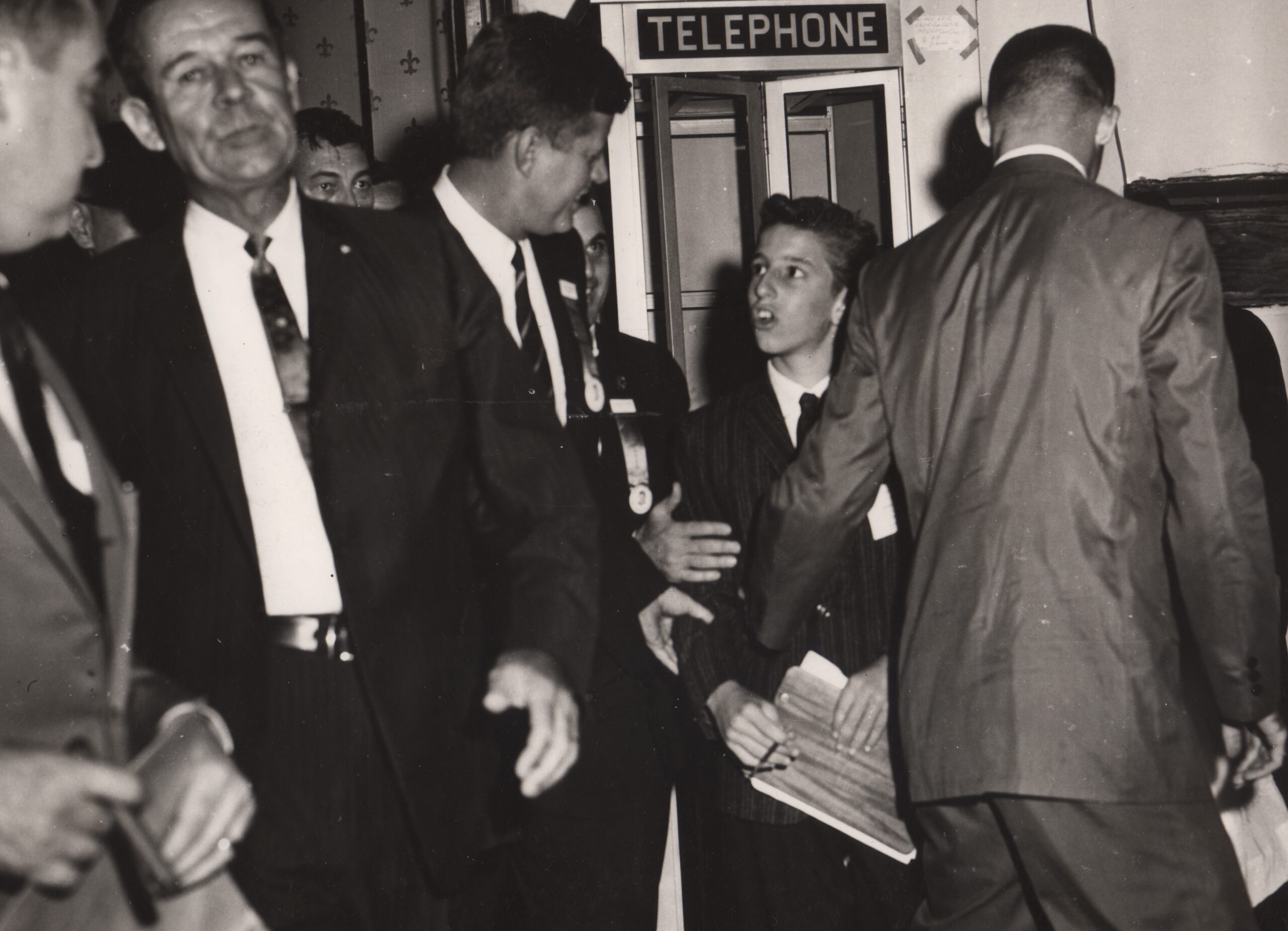 A black and white photo of a young boy shaking the hand of John F. Kennedy
