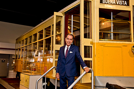 Dr. George standing on the steps of a yellow old Miami trolley
