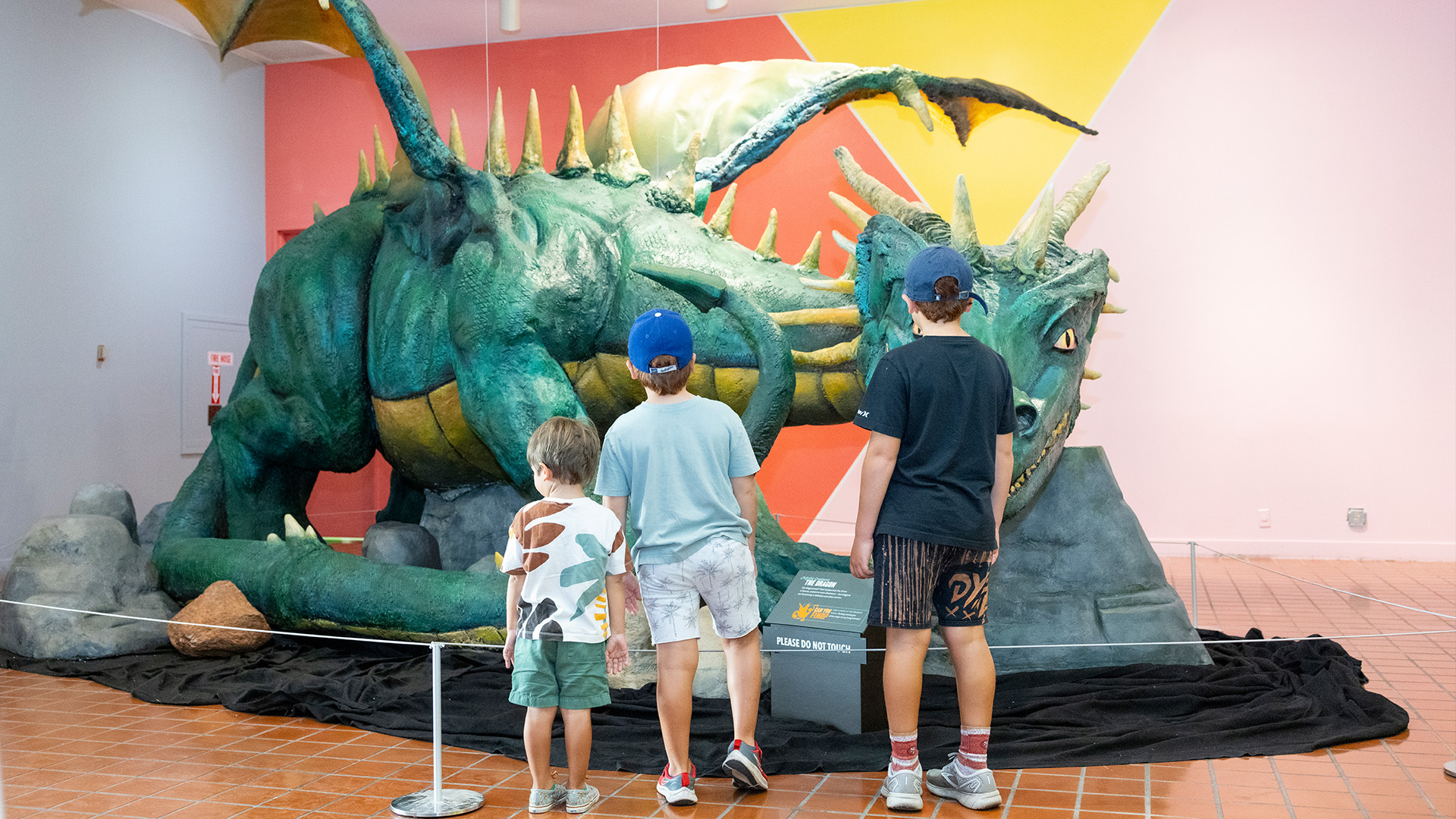Children standing in front of large green dragon.