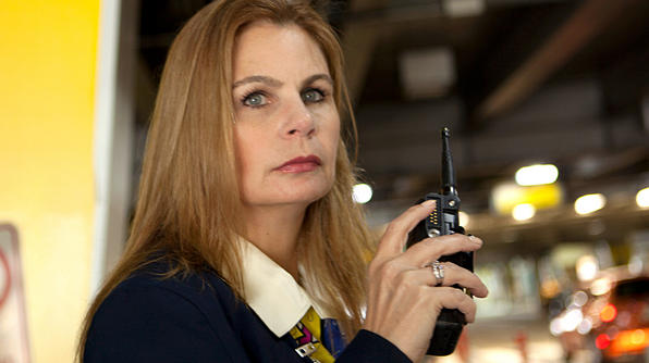 A close-up shot of a woman who is looking off-camera holding a walkie talkie