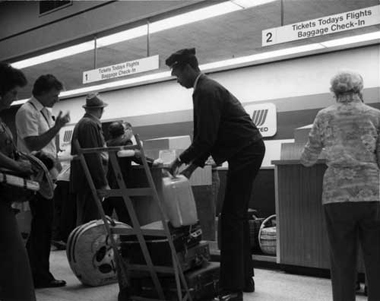 A skycap helps passengers with baggage check-in. March 1976. City of Miami Collection, HistoryMiami. CM-12958.