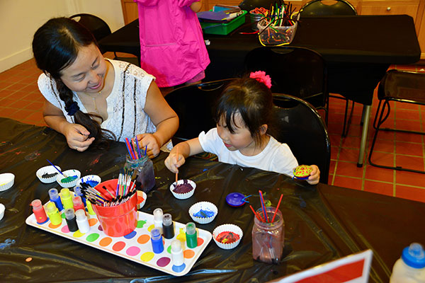 Mom and daughter sitting at a table surrounded by water colors painting at a Family Fun Day event