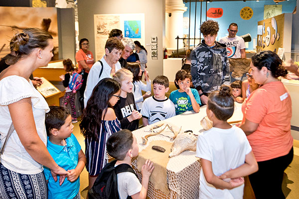Group of children and adults standing around a tables looking at an activity