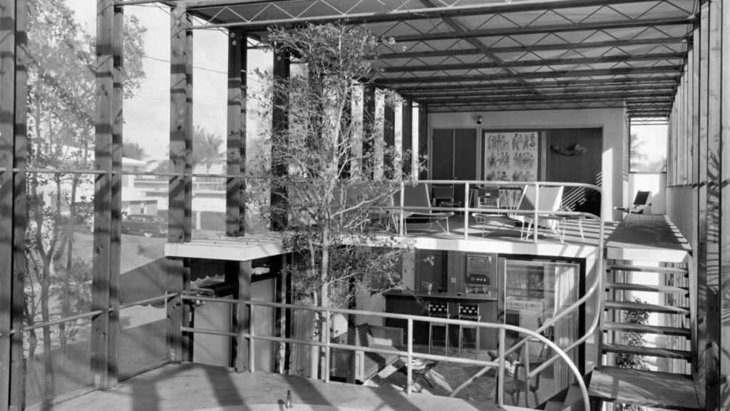 Black and white image of the interior of a glass sided house.