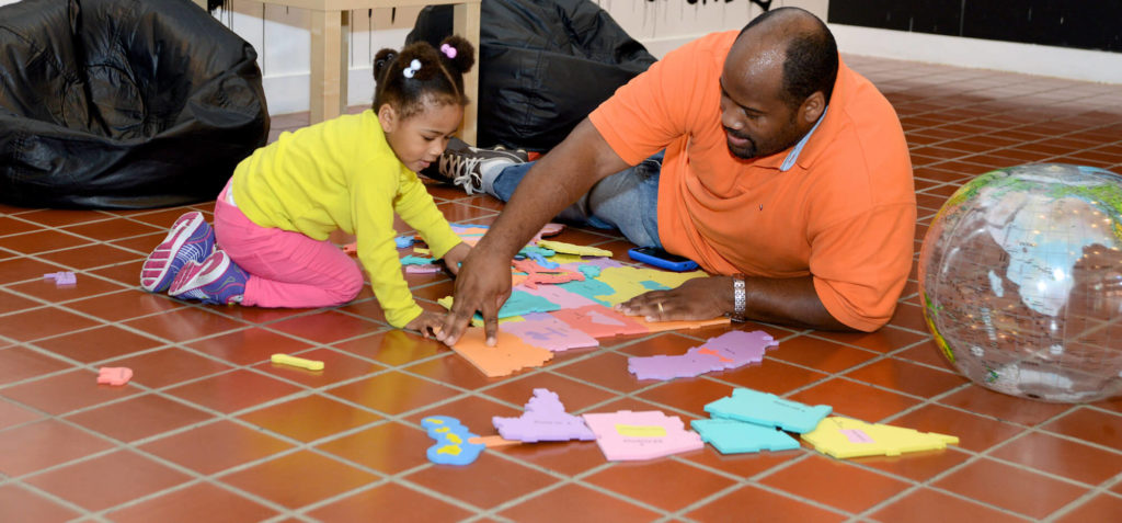 black man making puzzle with daughter