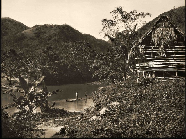 old wooden house in tropics with river and mountain in background