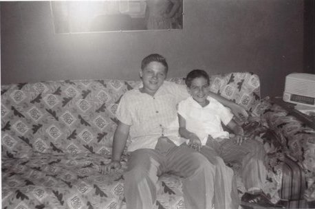 Black and white photo of two young boys, Jerry and Howard Wallach, sitting on a couch. The older boy has his arm around the younger one.