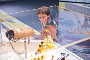 Child looking at USS Maine boat in gallery.