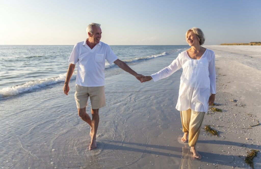 two older adults holding hands on the beach